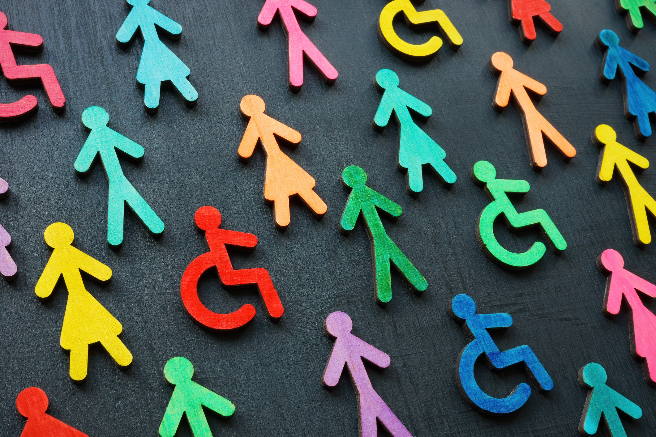 numerous colorful figures representing people and handicapped people on a dark gray background