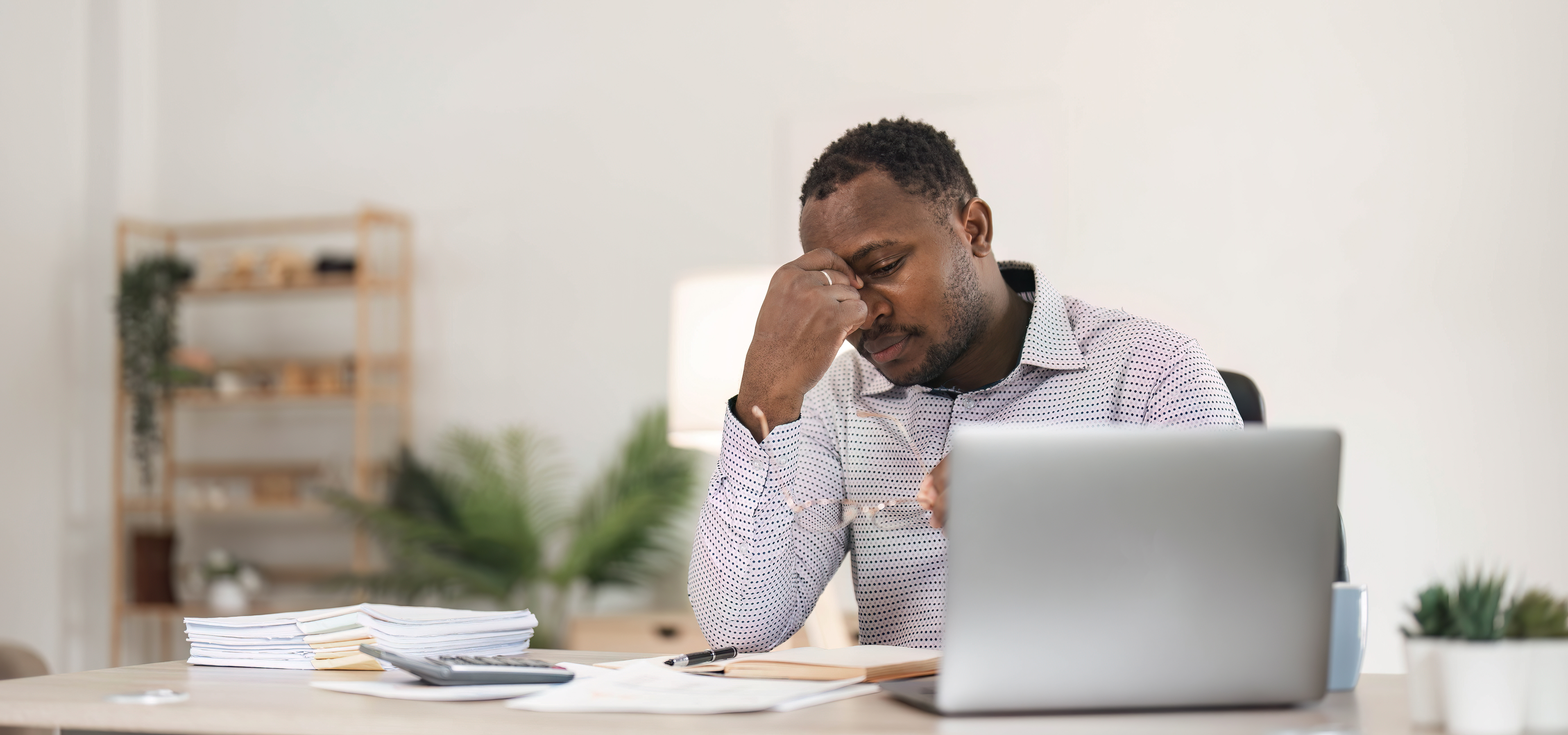 stressed out man with bills and laptop in front of him on the table
