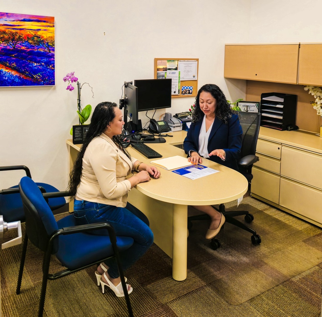 two people having a discussion at a desk in an office