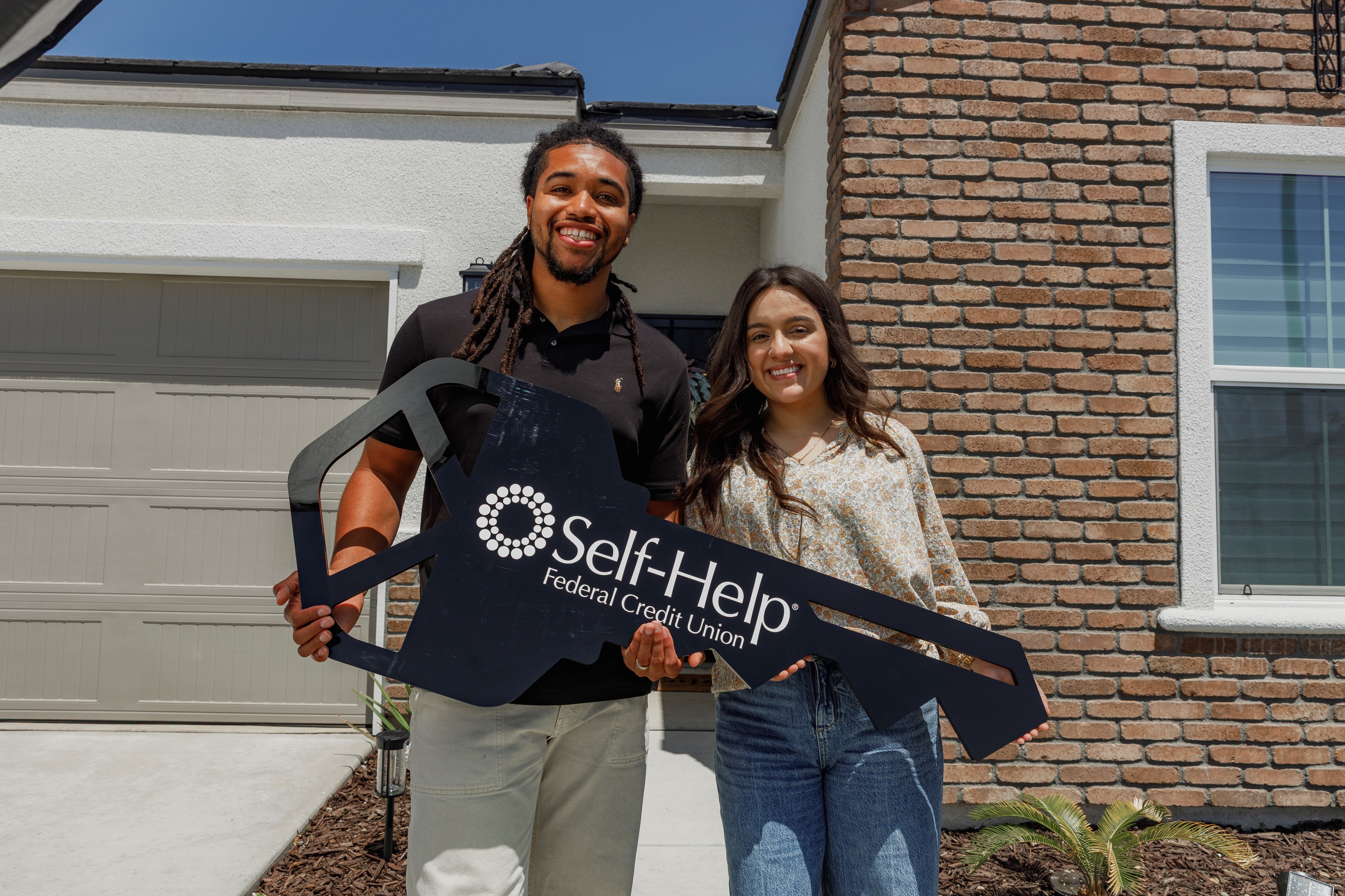 Self-Help members, Jesse and Alex, holding a large key shaped-sign that reads