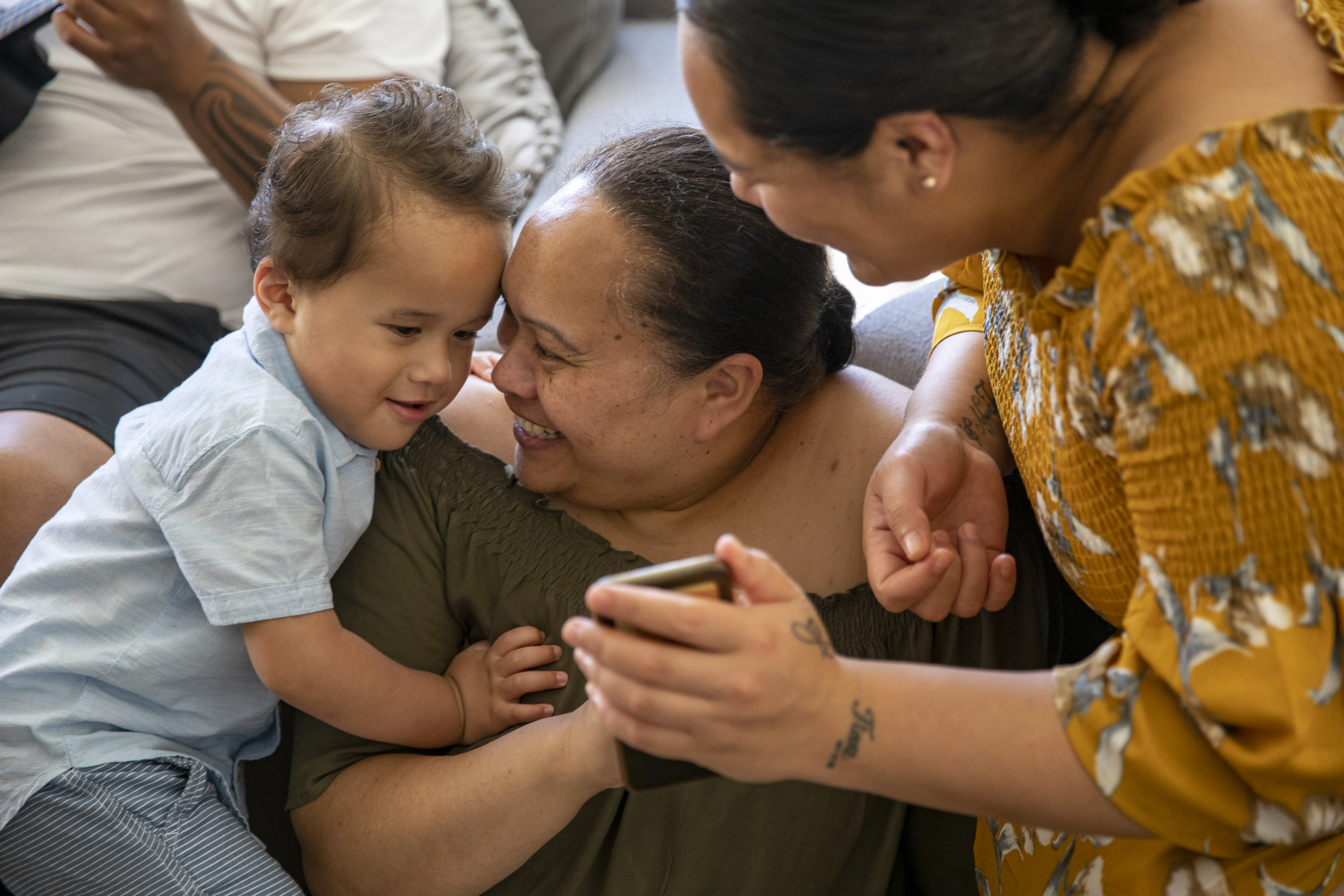 Pacific Islander Family showing a baby a phone while smiling